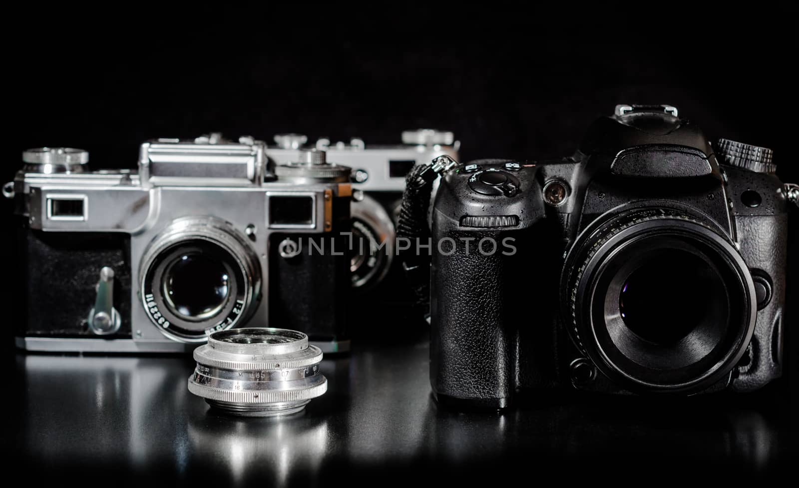 two vintage cameras with lens and one modern camera on a black background closeup