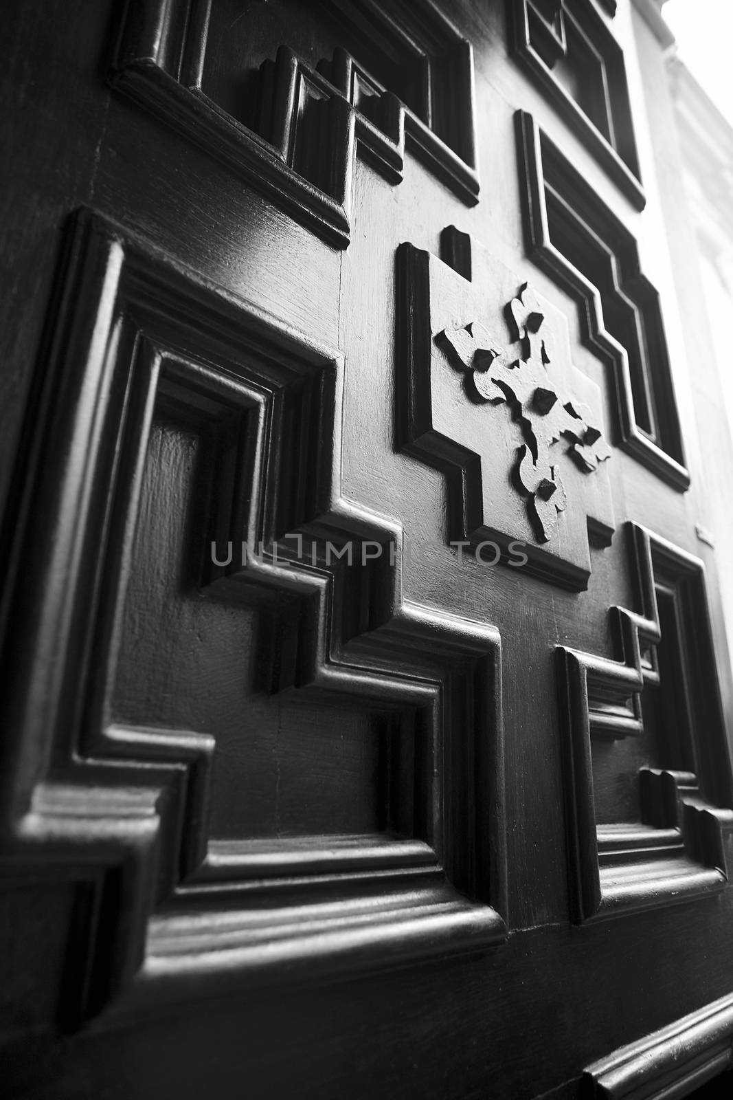 Detail of a vintage wooden door with geometric decorations and inlays.