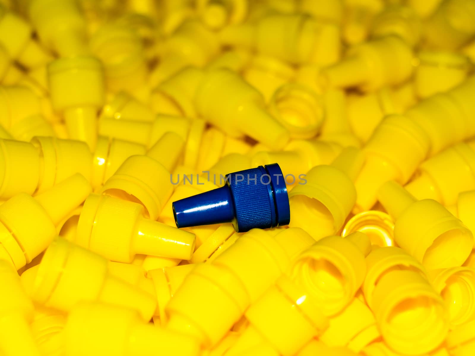 texture yellow plastic caps with one blue lid closeup