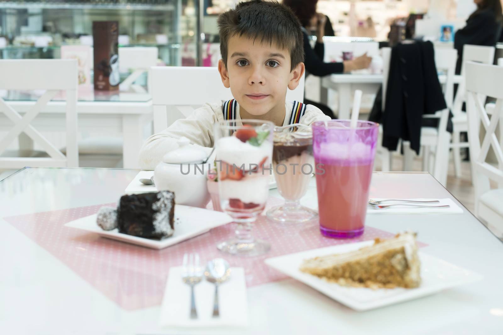 Cake and a milkshake in confectionery. Child on a table