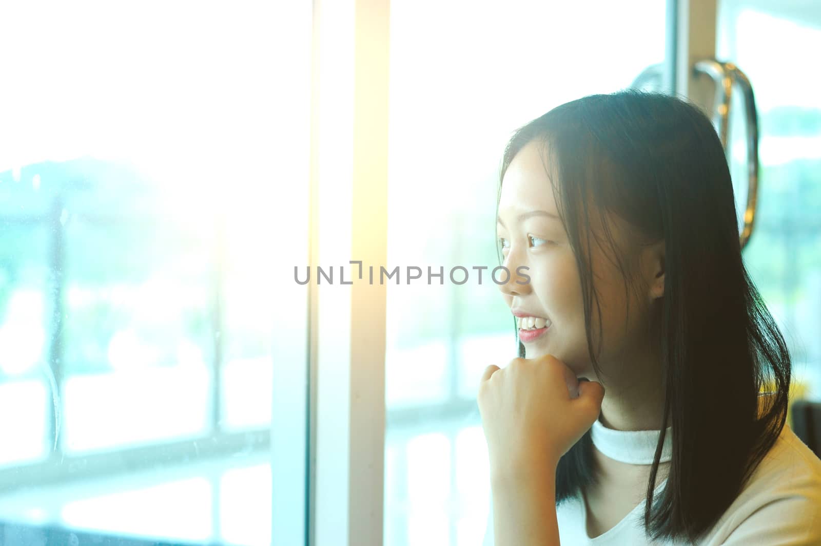 Side view portrait of a young asian girl looking through a window at restaurant
