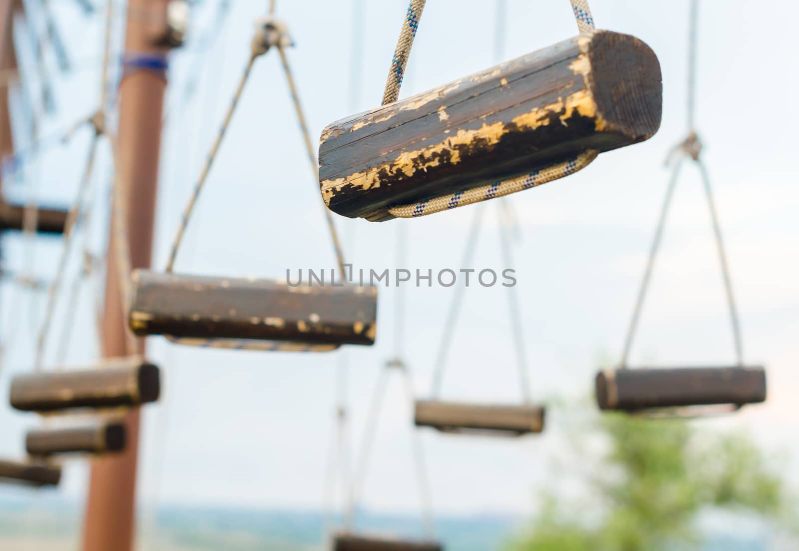 small wooden logs of a suspended rope road close-up against a blue sky
