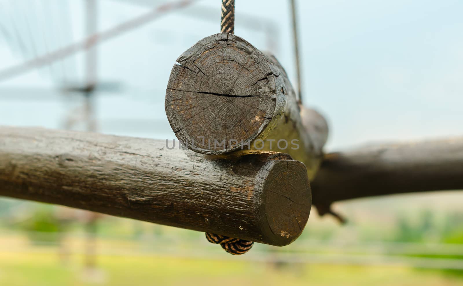 small wooden logs of a suspended rope road close-up against a blue sky