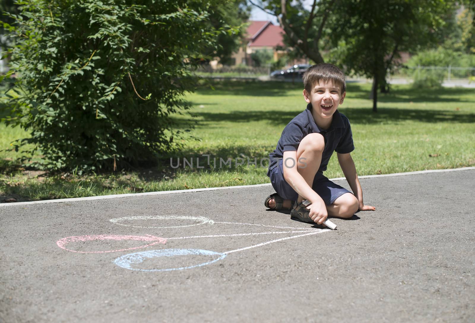Child drawing balloons on asphalt in a park