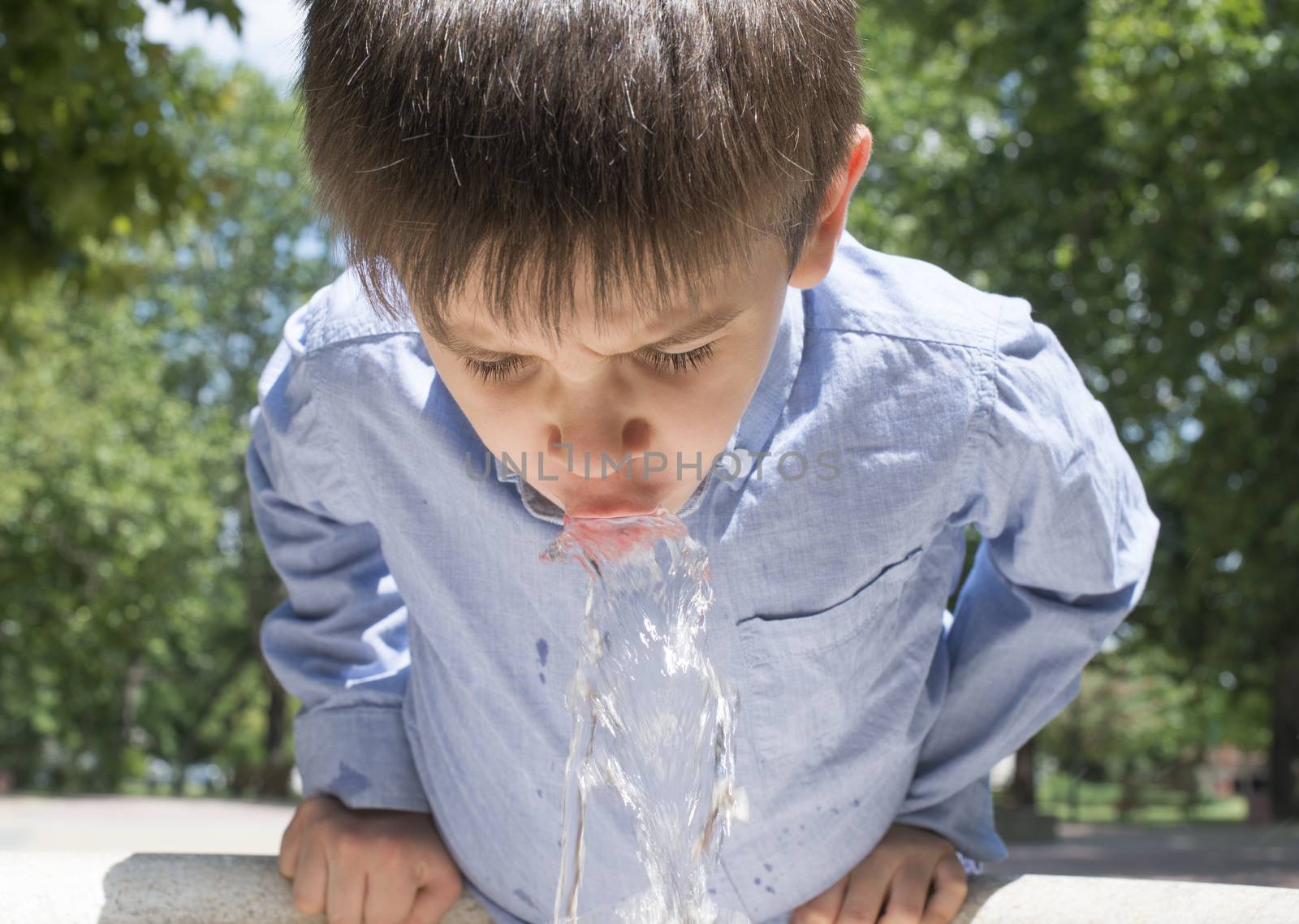 Child drinking water from a fountain. Close up