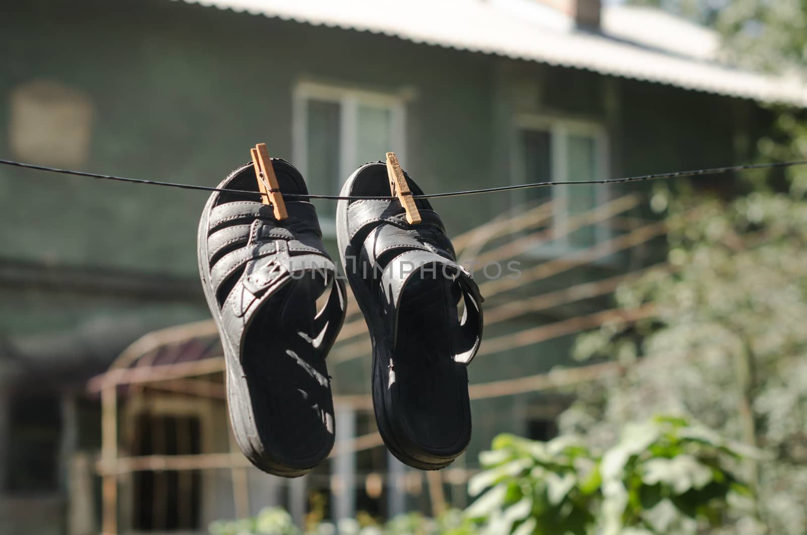 thin slippers hang on a rope with clothespins on the background of an old house