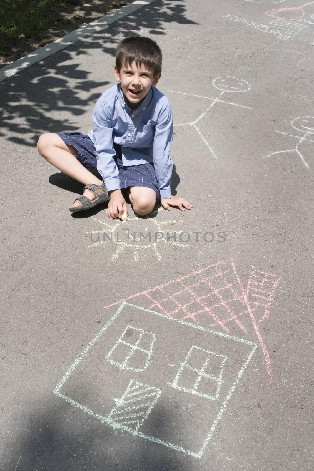 Child drawing sun and house on asphal by deyan_georgiev
