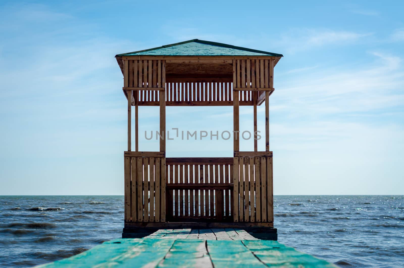 wooden arbor on the background of the sea and blue sky with clouds