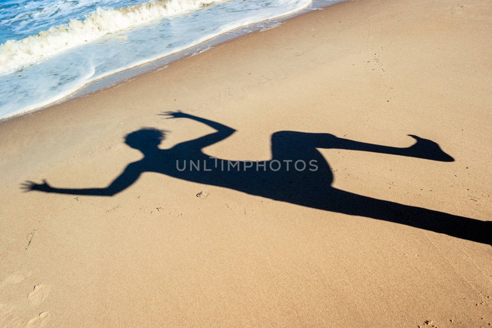 shadow of a dancing girl on the sea sand on the beach near the sea