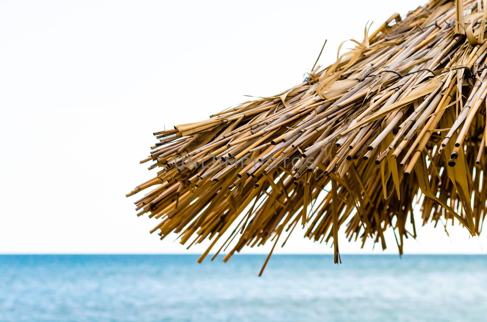 fragment of a straw beach umbrella against the background of the sea