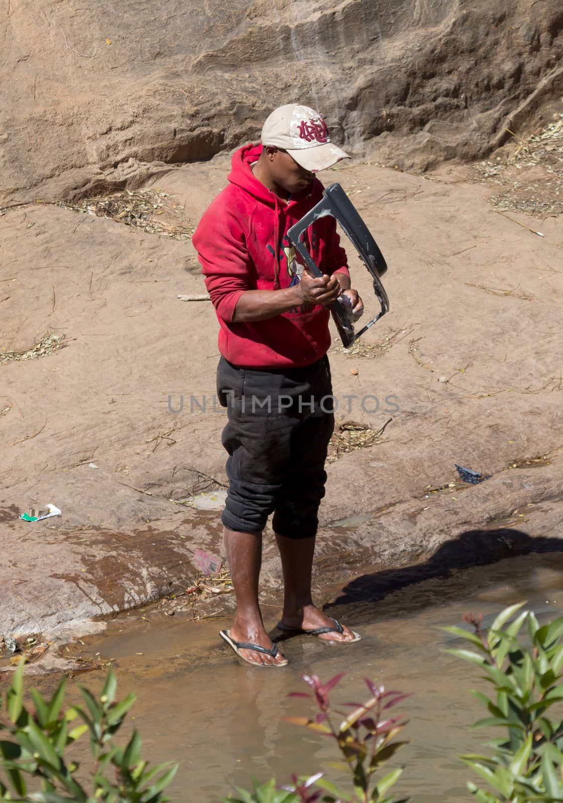 Madagascar on july 26, 2019 - Man washing carparts by hand, getting them ready to sell