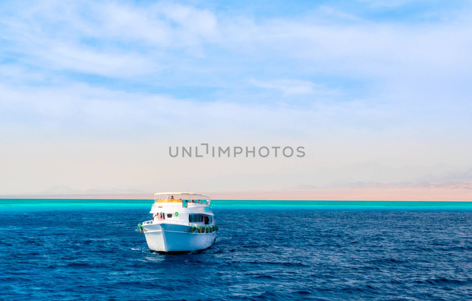 landscape tourist boat in the Red Sea on the background of a rocky shore and blue sky and clouds in Egypt in Sharm El Sheikh