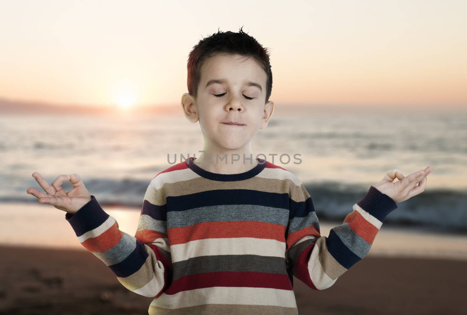 Child meditate on the beach sunrise. 