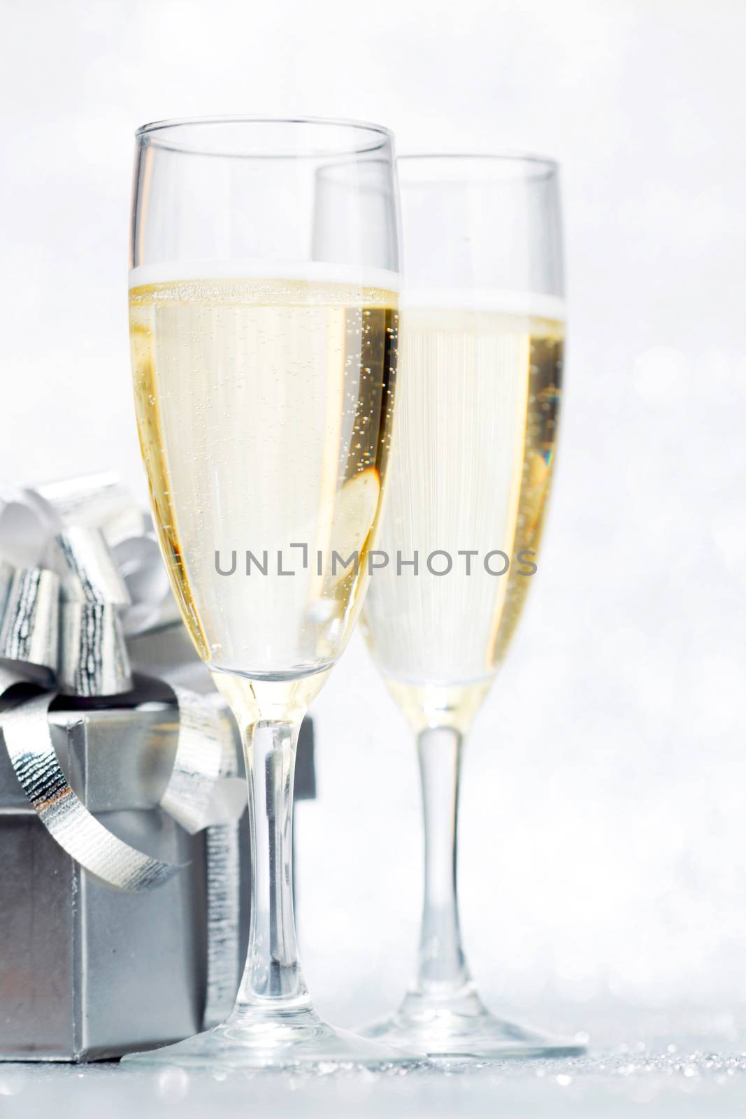 Glasses of champagne and silver gifts isolated on white