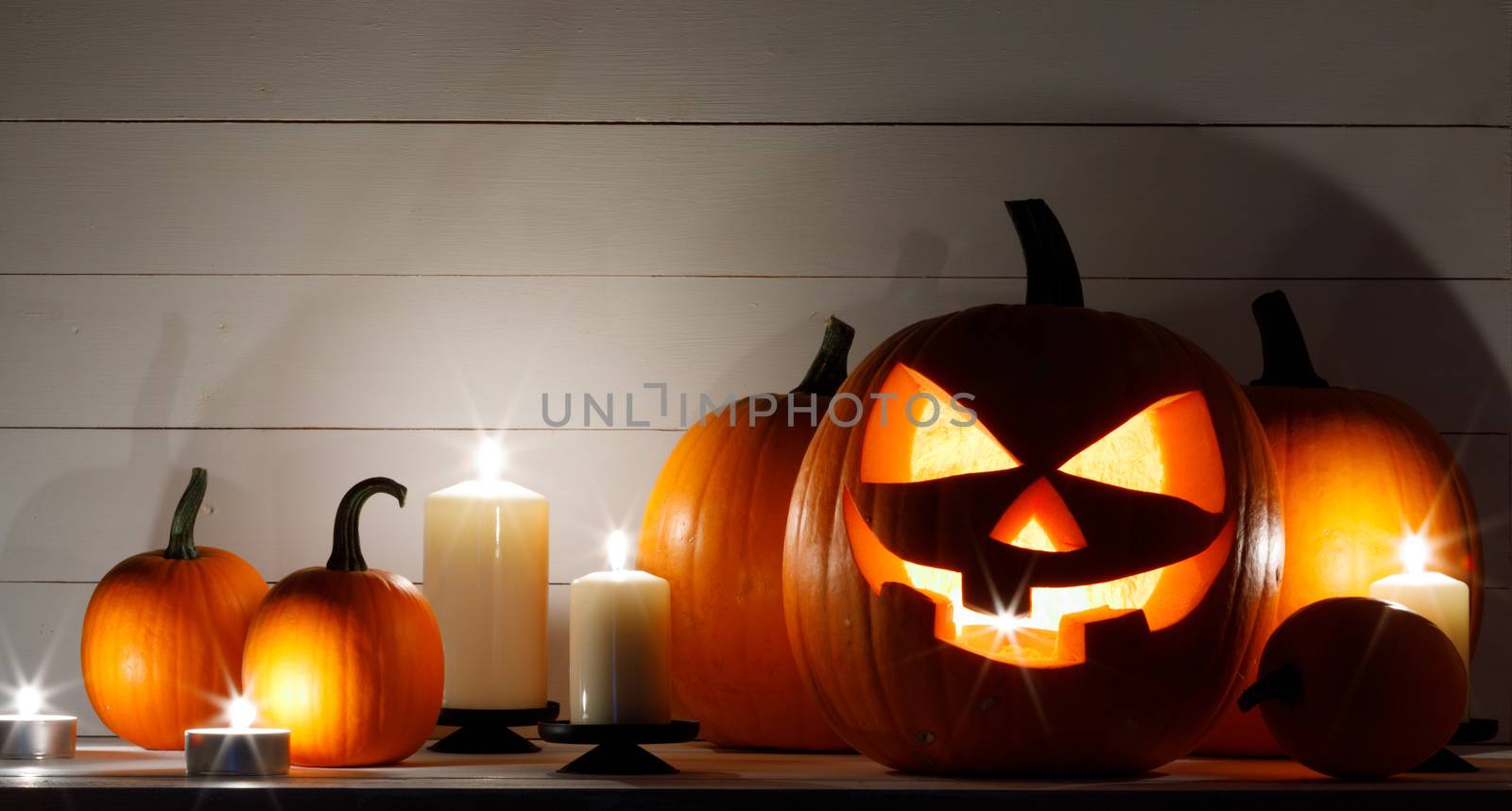 Group of Halloween pumpkin head jack o lantern and candles on dark wooden background