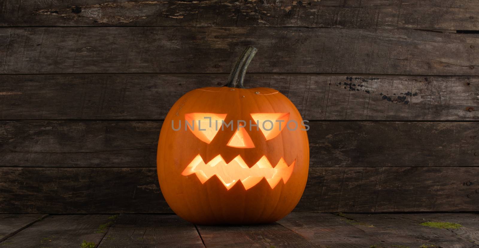 Glowing Halloween pumpkin head jack lantern on old wooden background