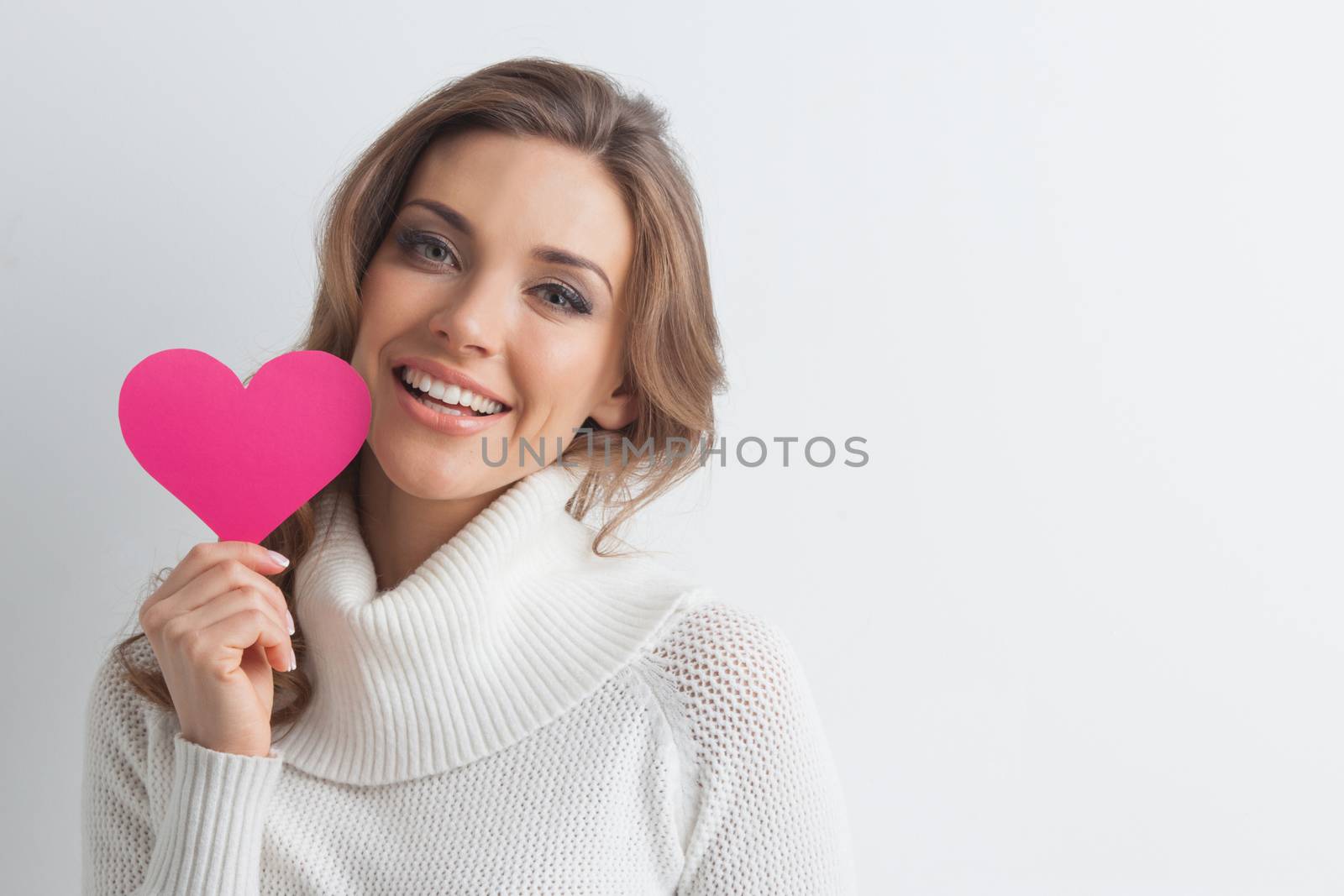 Happy young smiling woman with pink paper heart