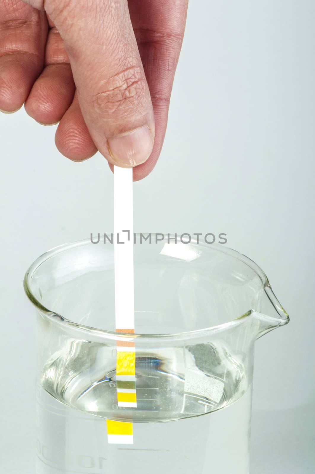 Litmus strips for measurement of acidity.Beaker with water