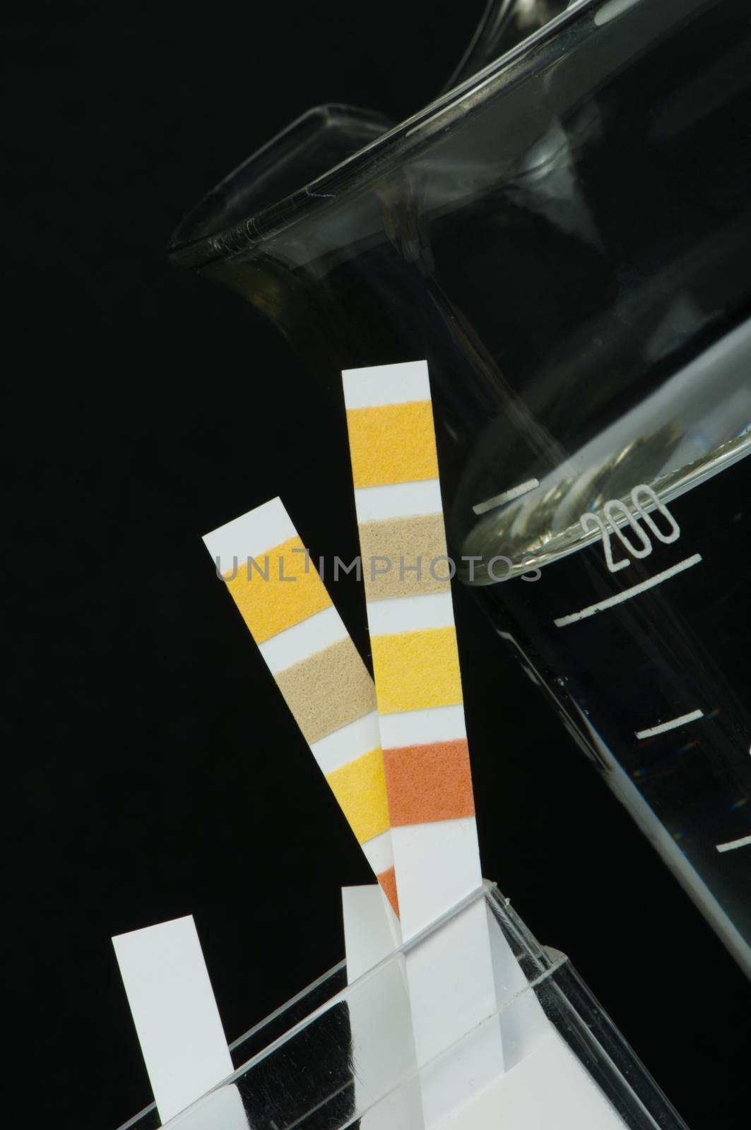 Litmus strips for measurement of acidity.Beaker with water
