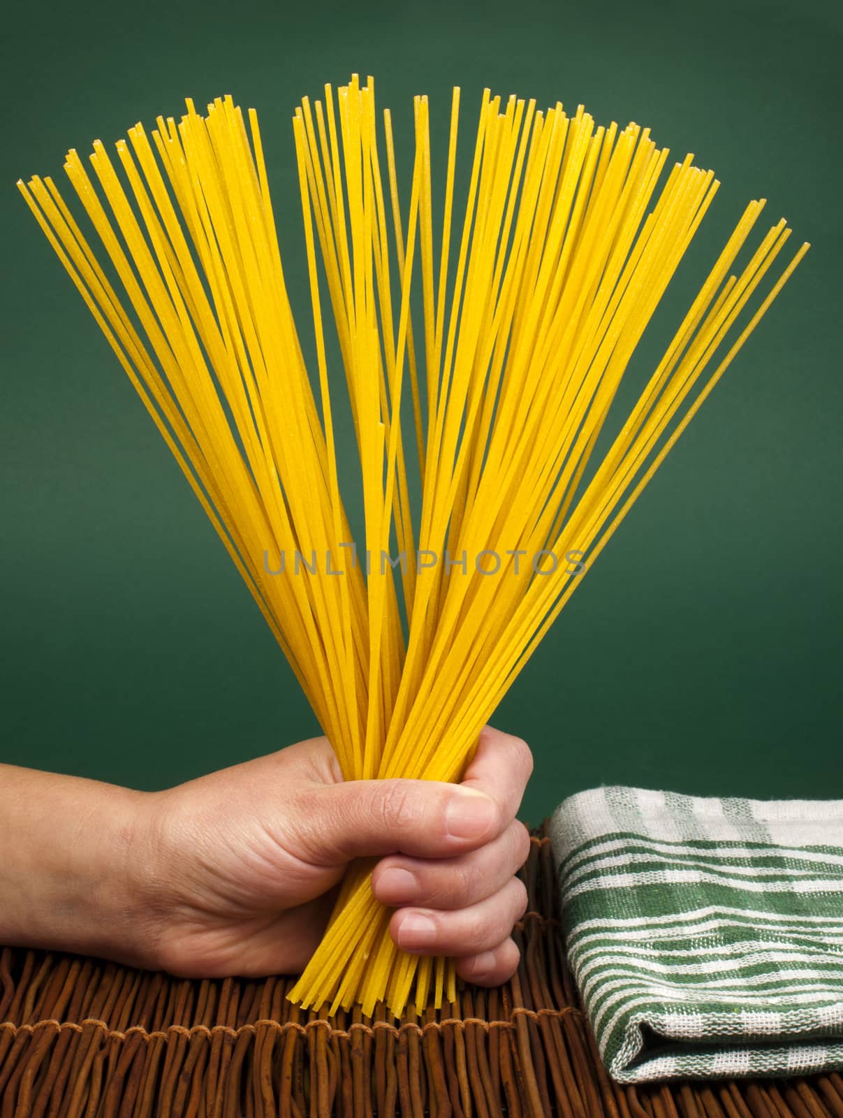 Female hand holding spaghetti. Green background