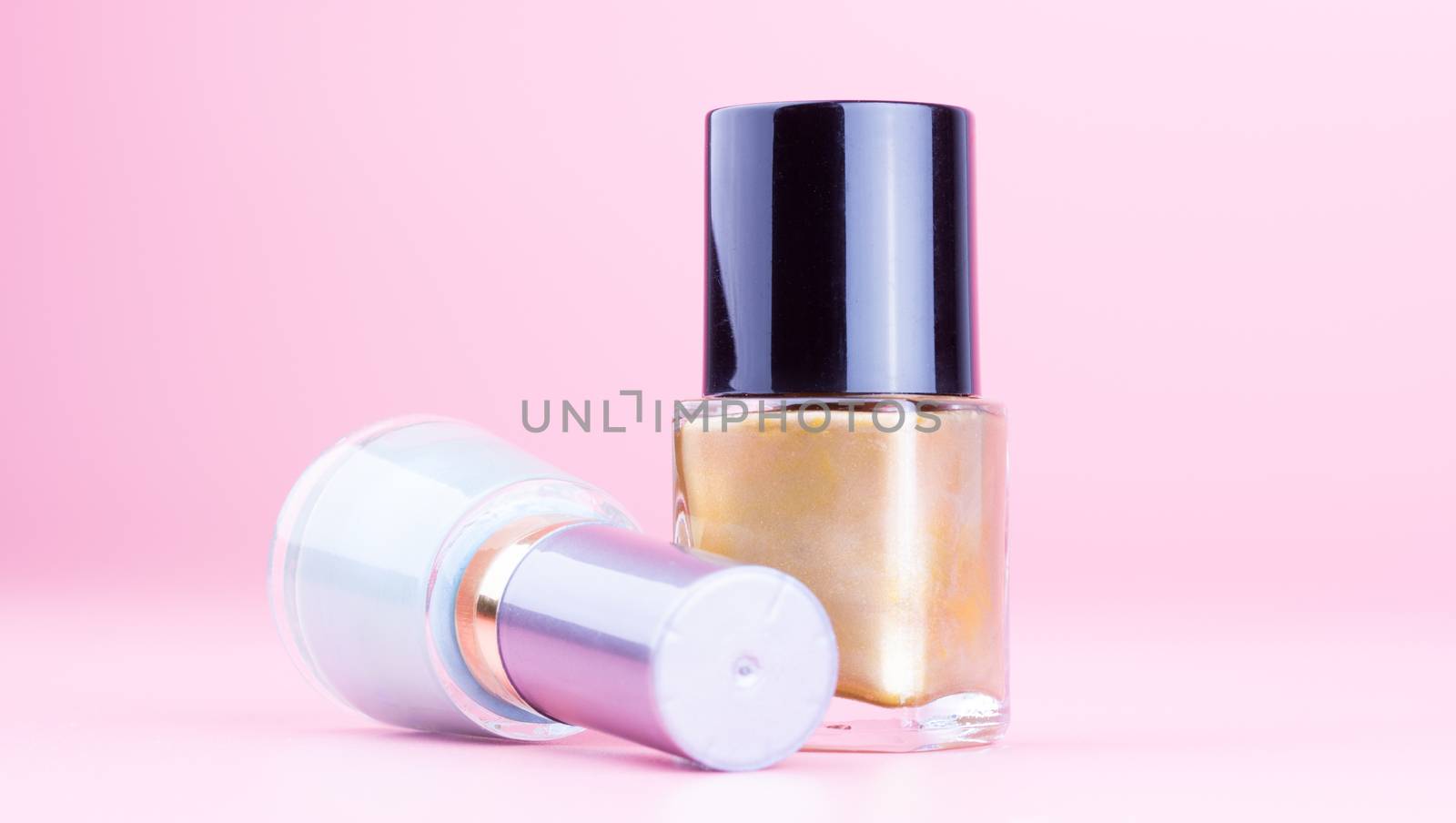 Two bottle of nail polish on pink background