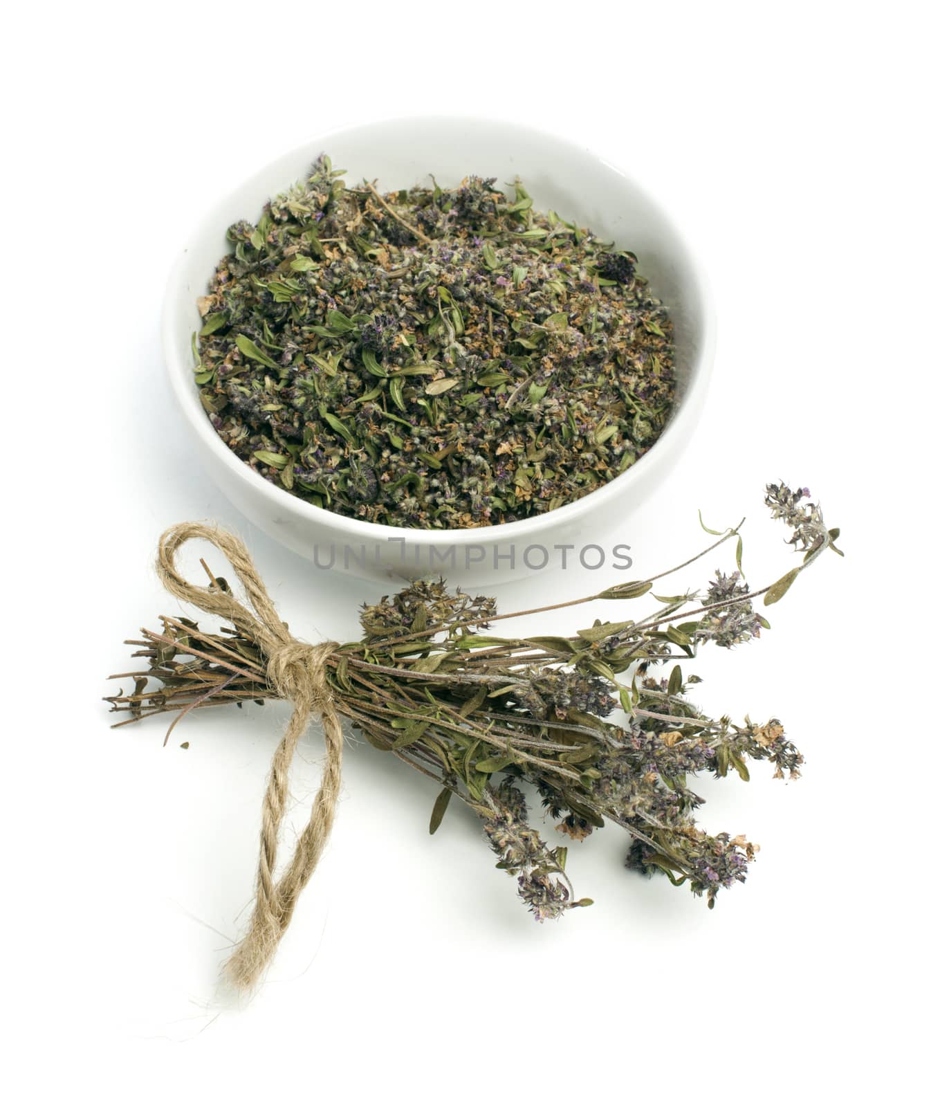 Dried thyme in a bowl and thyme twigs on white background