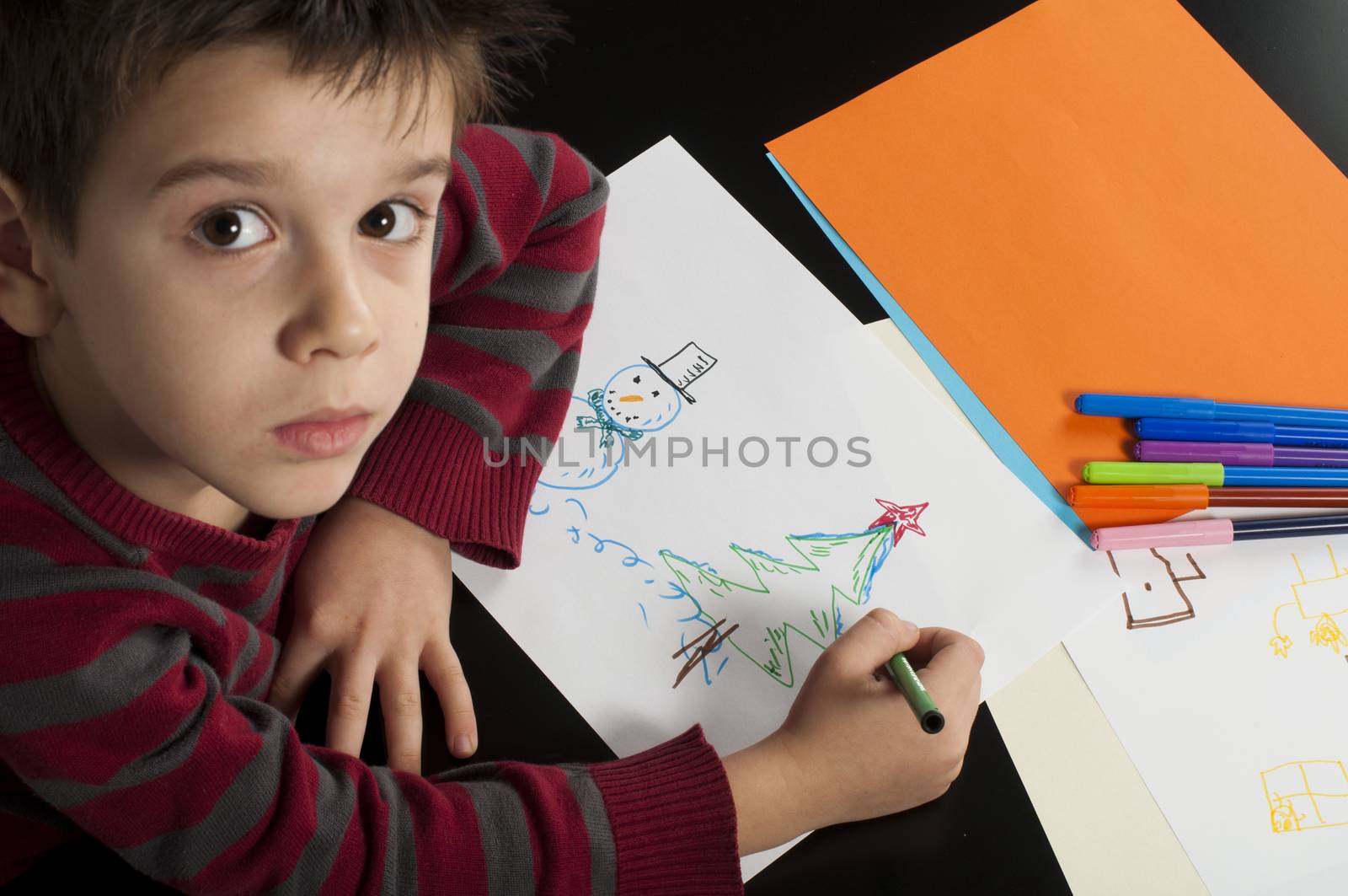 Boy drawing with markers. Multicolored papers