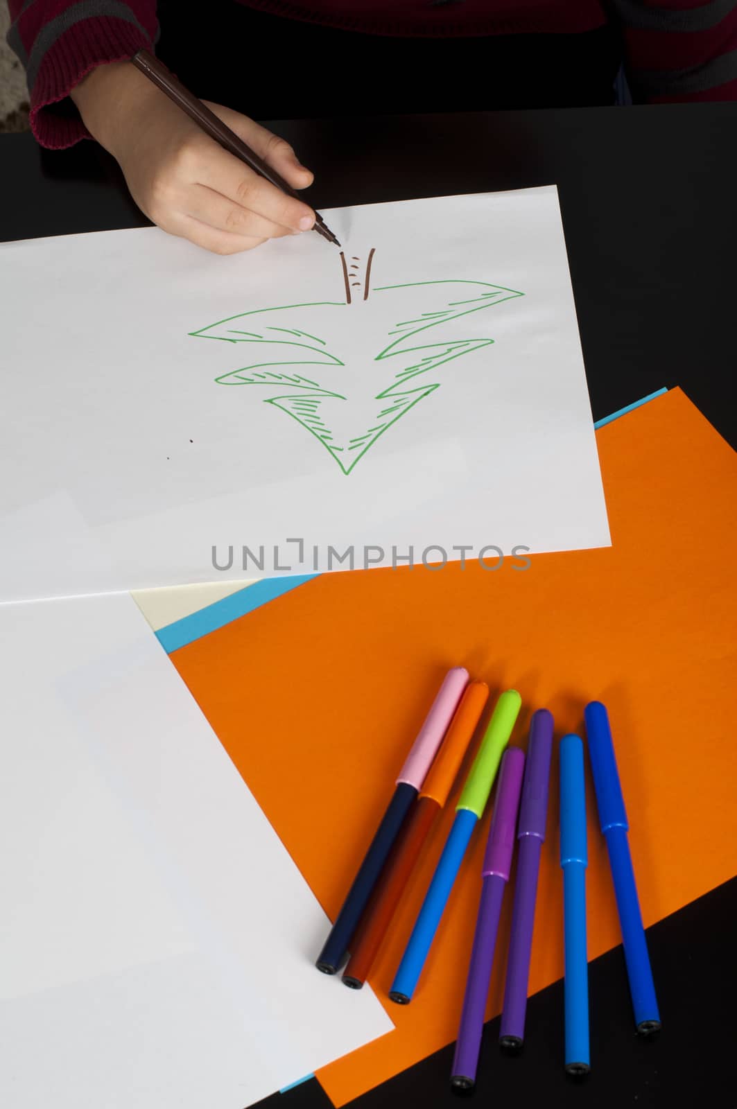 Boy drawing with markers. Multicolored papers