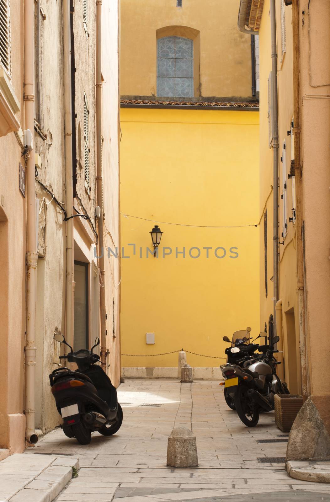 Scooters parked at the old buildings. St. Tropez street and buildigs.