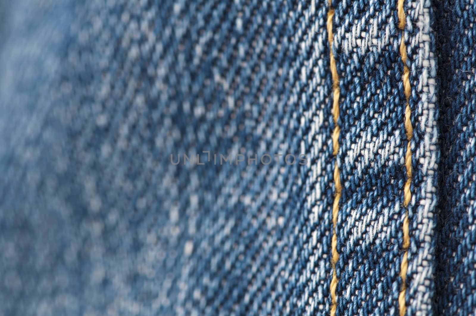 Orange stitch on the denim garment very close up.Jeans background