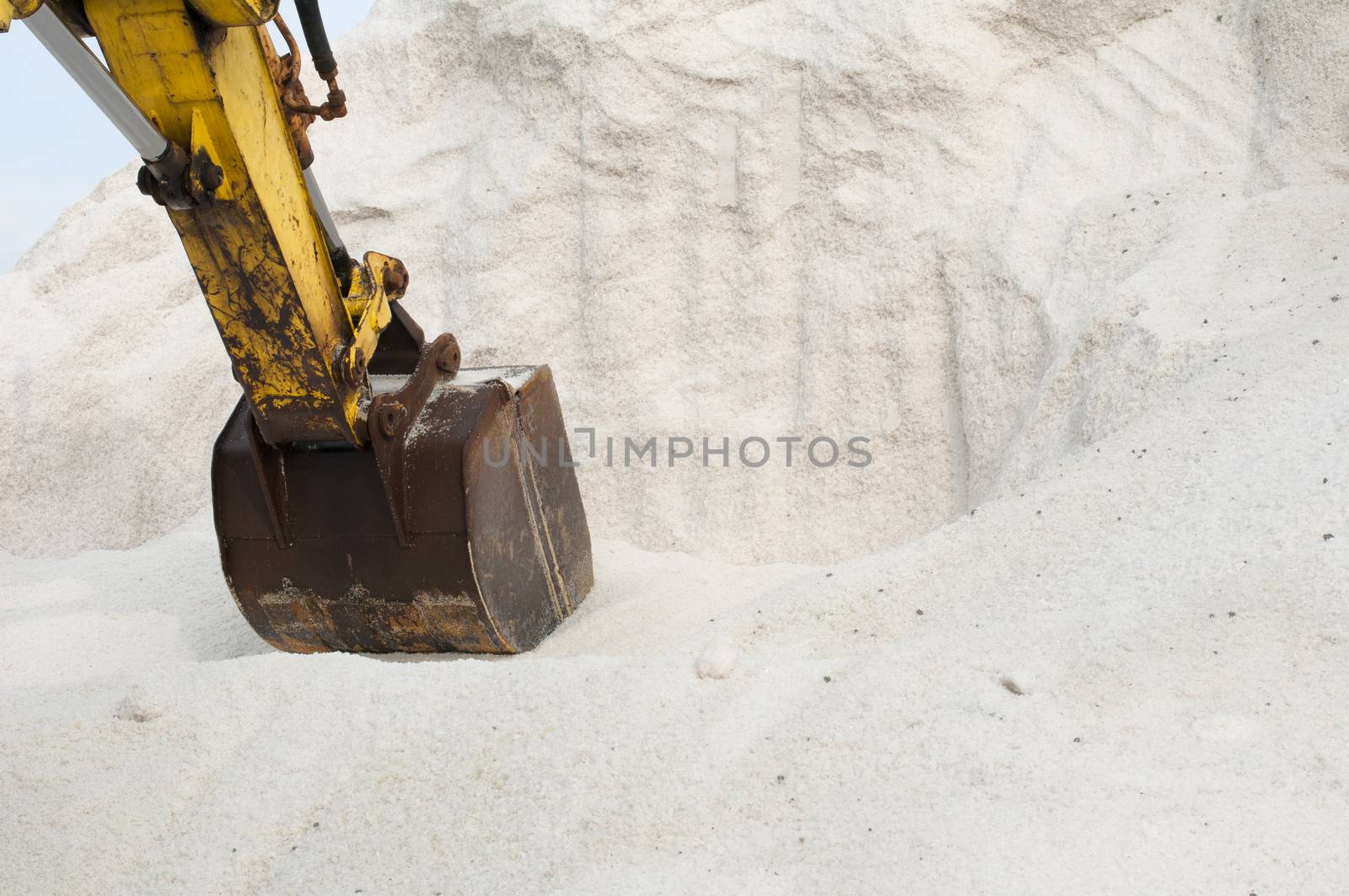 Excavator digging pile white salt