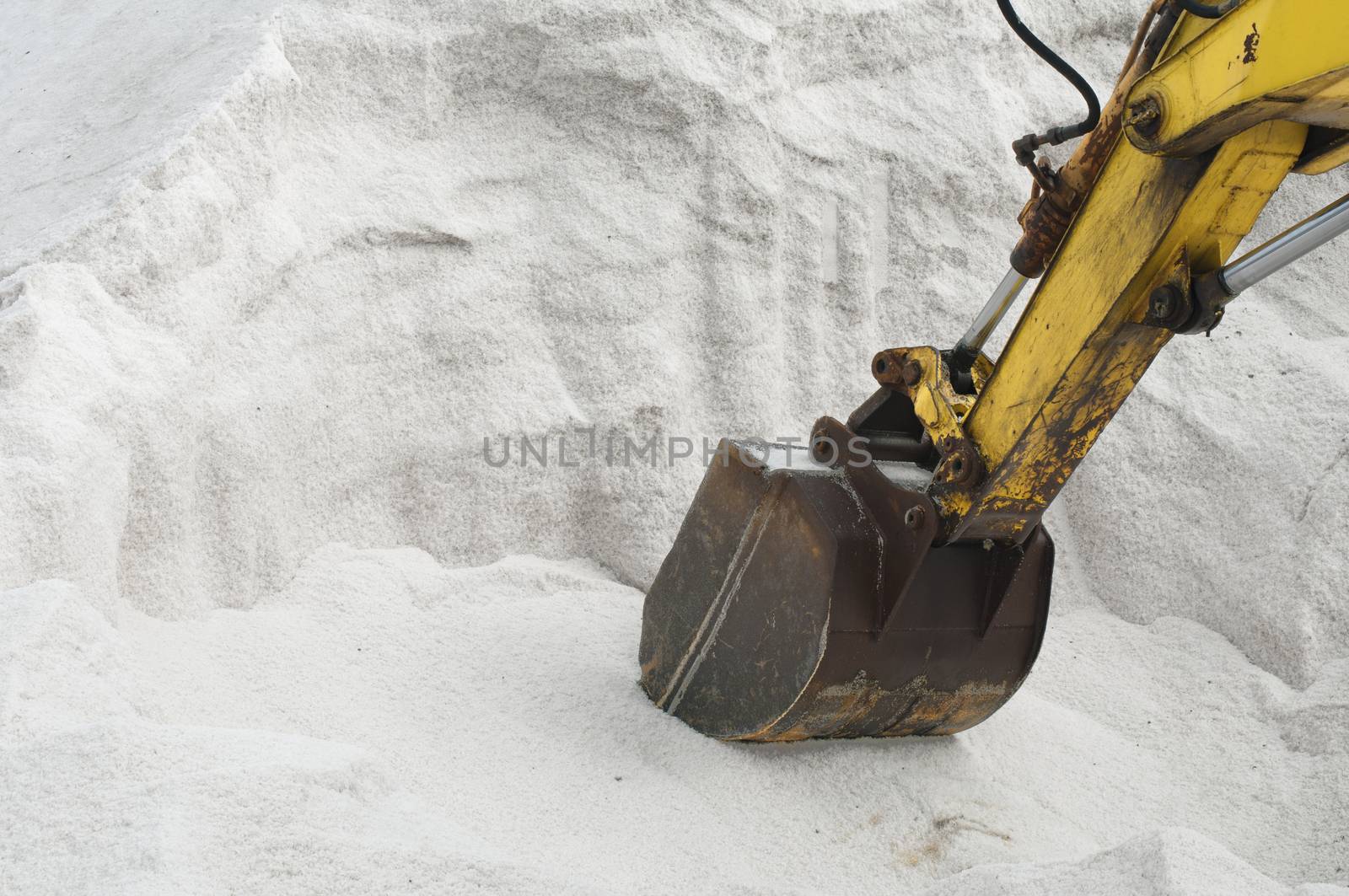 Excavator digging pile white salt