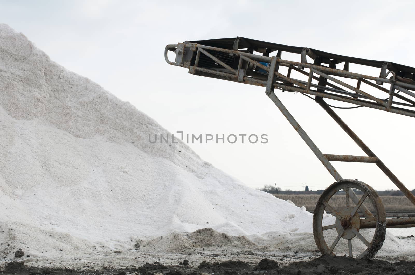 Conveying belt on sea ​​saltern. White pile