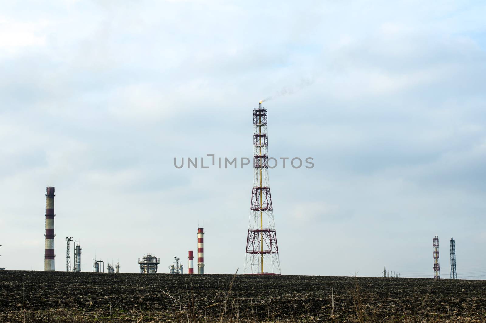 Oil and chemical refinery for production of petroleum products. Land on foreground. Flame