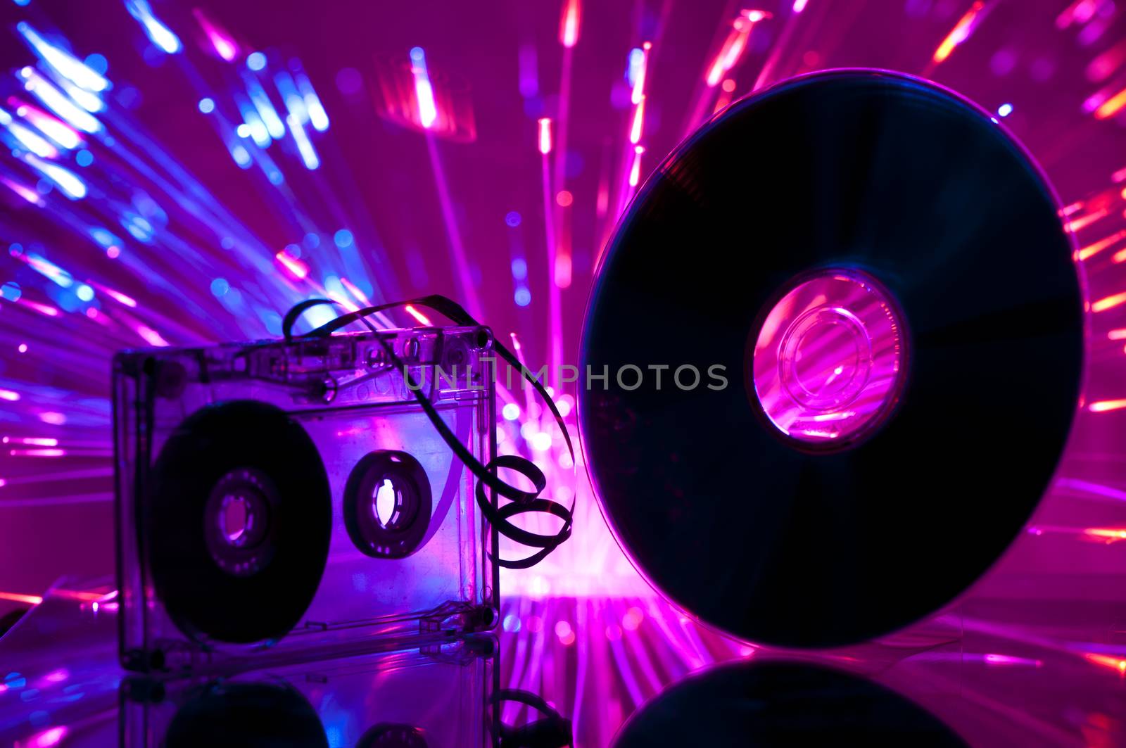 Cassette tape and CD. Multicolored blue lights on background