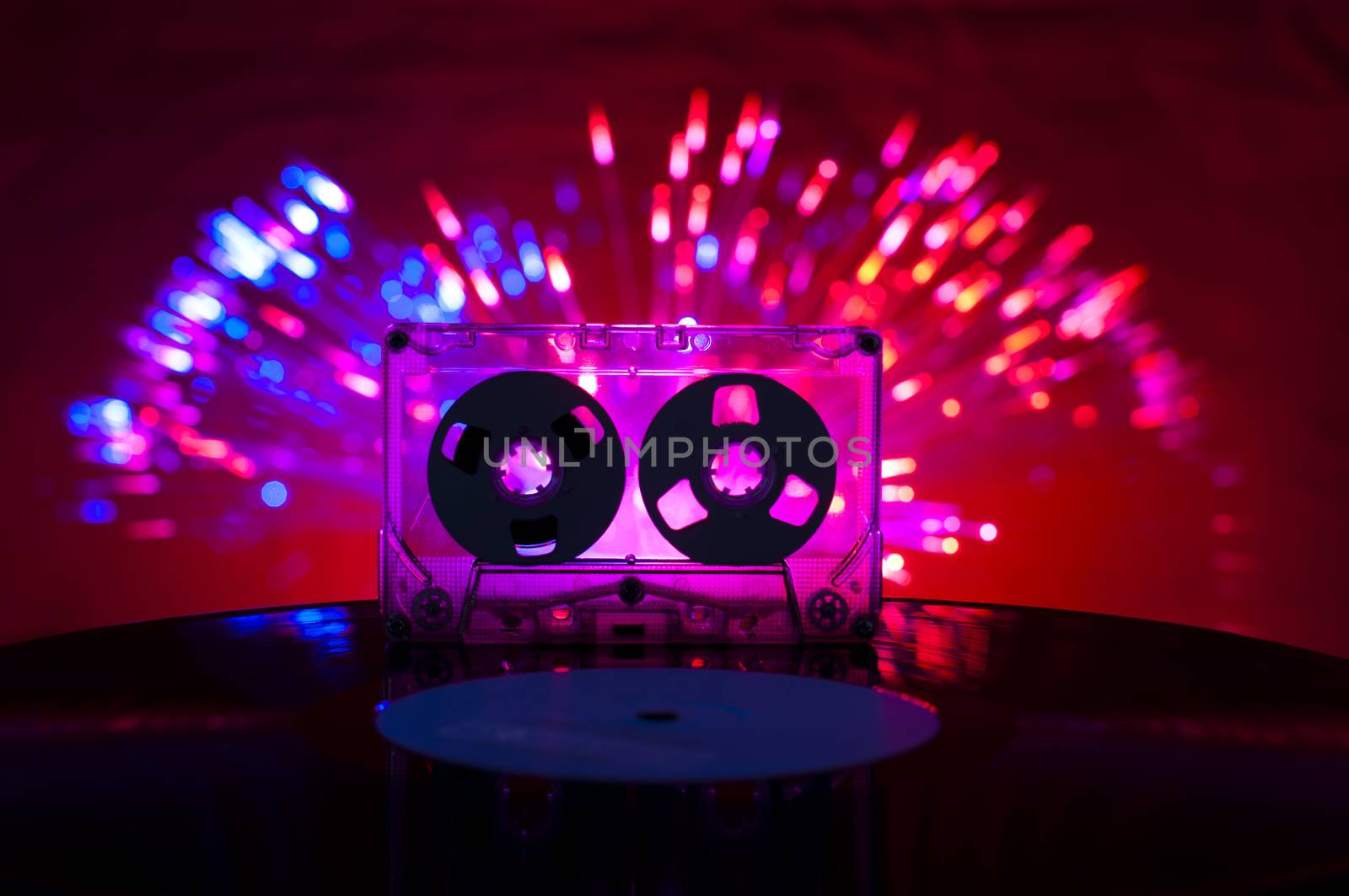 LP vinyl record, cassette tape and disco lights on background