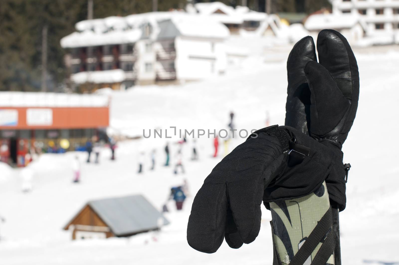 Ski gloves and sticks. Winter tourists on the background.