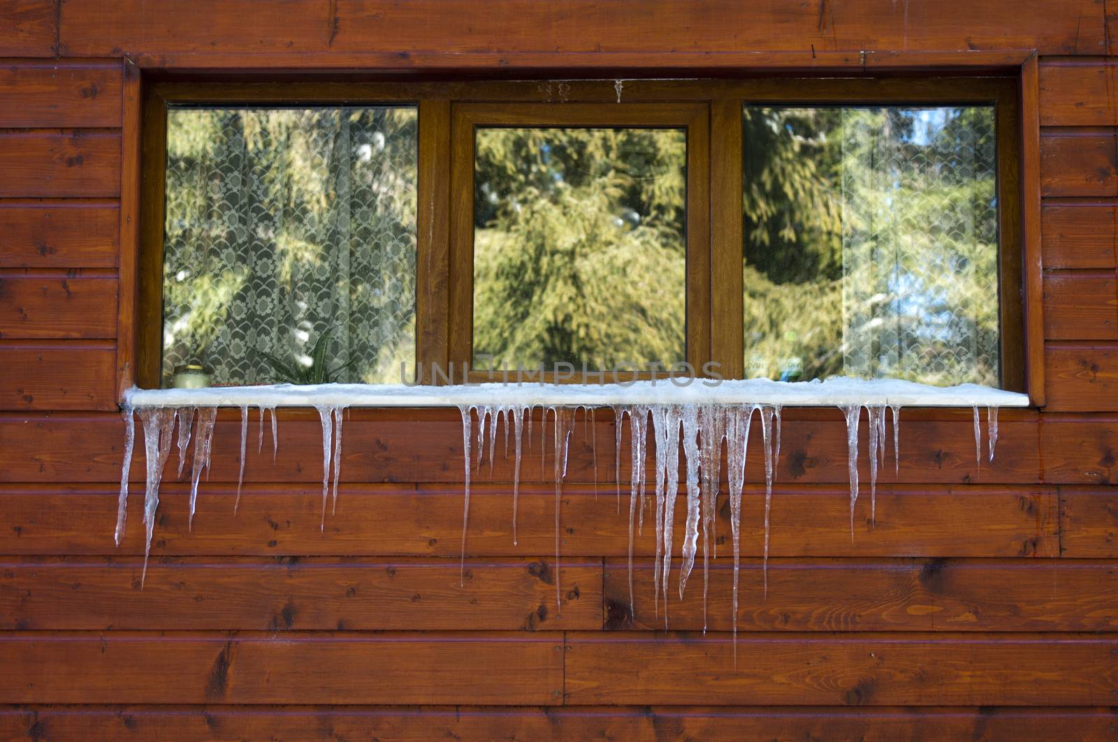 Icicles on window. Wooden house windows