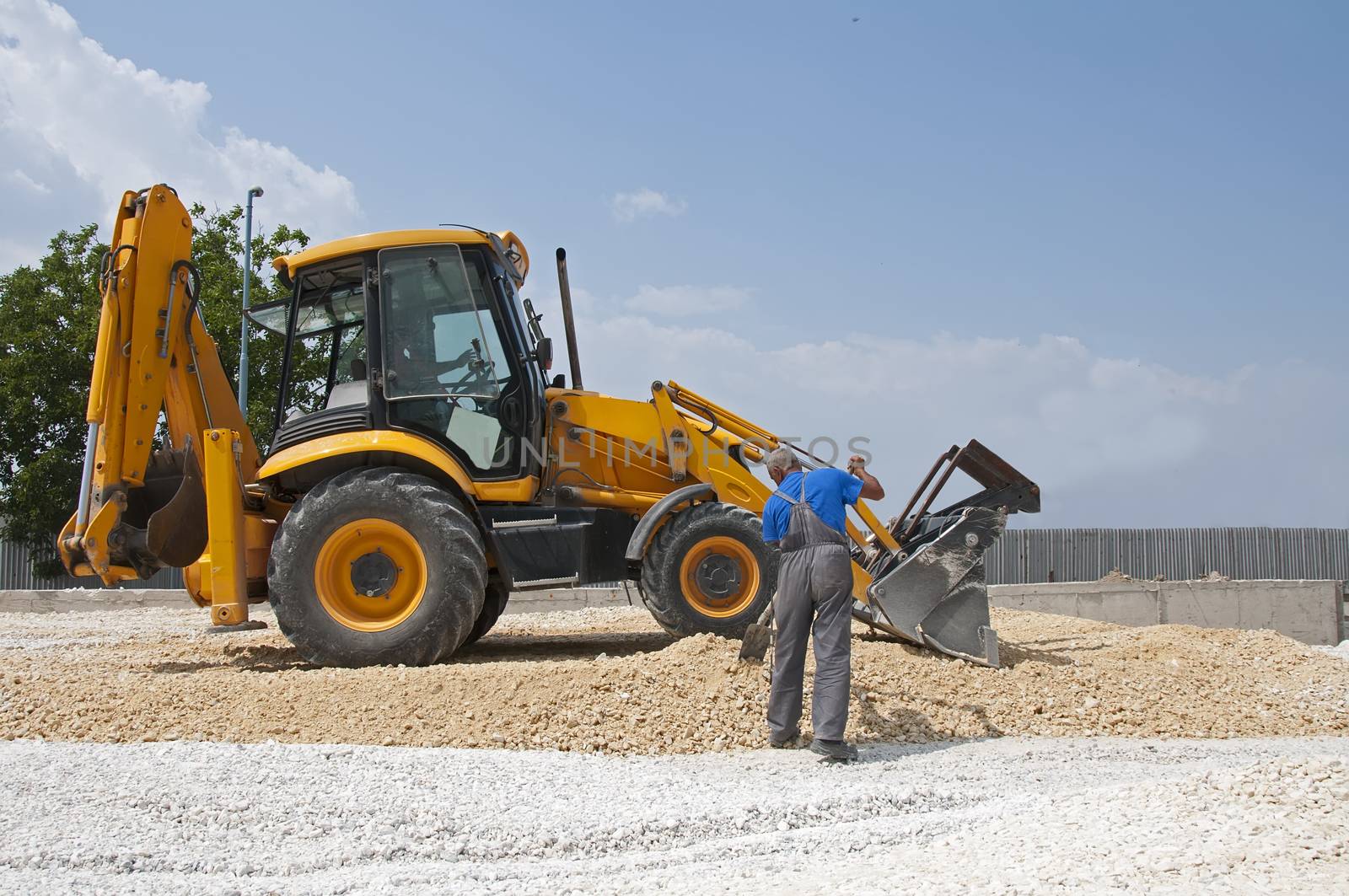 Worker and gravel excavator on blue sky 