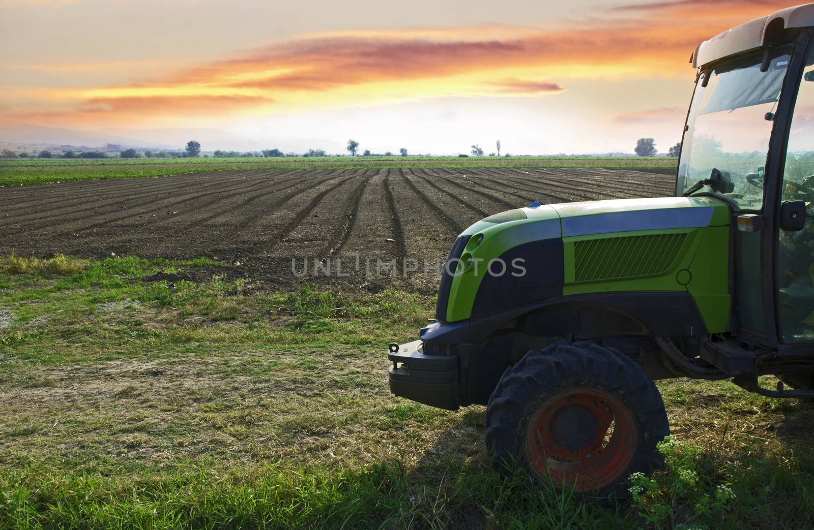 Plowed land and tractor on sunset