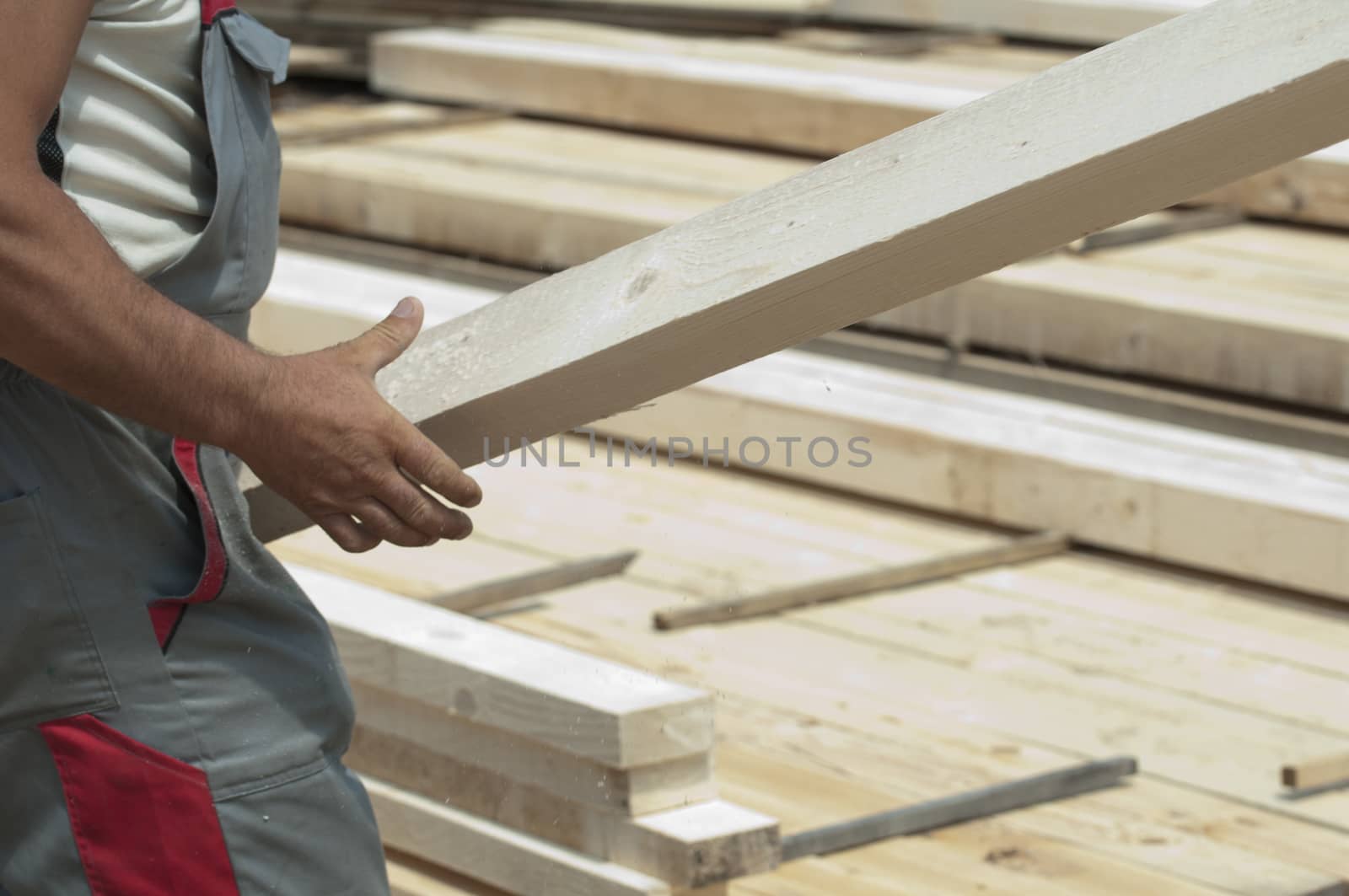 A worker moves a wooden beam