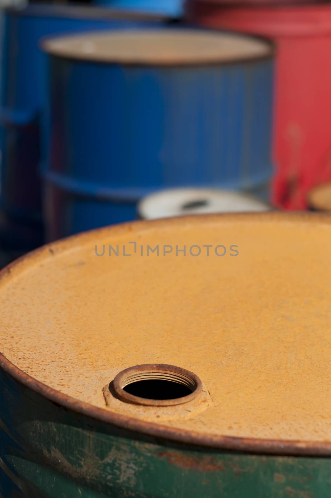 Old colored barrels for oil products. Empty rusted drums