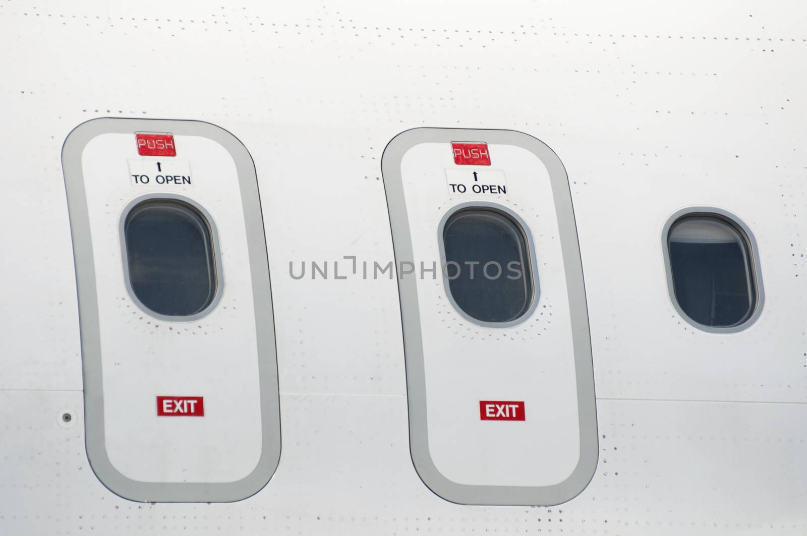 Windows of an airplane outside. White color plane. Two doors
