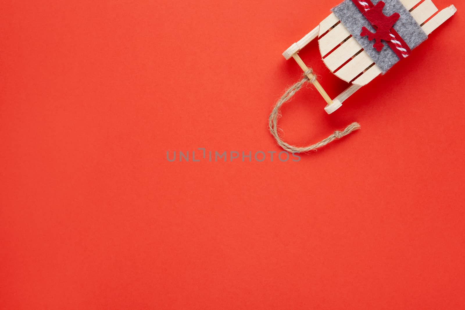 Christmas decoration, tree toy, wooden sled with deer on red background with copy space. Festive, New Year concept. Horizontal, flat lay. Minimal style. Top view.