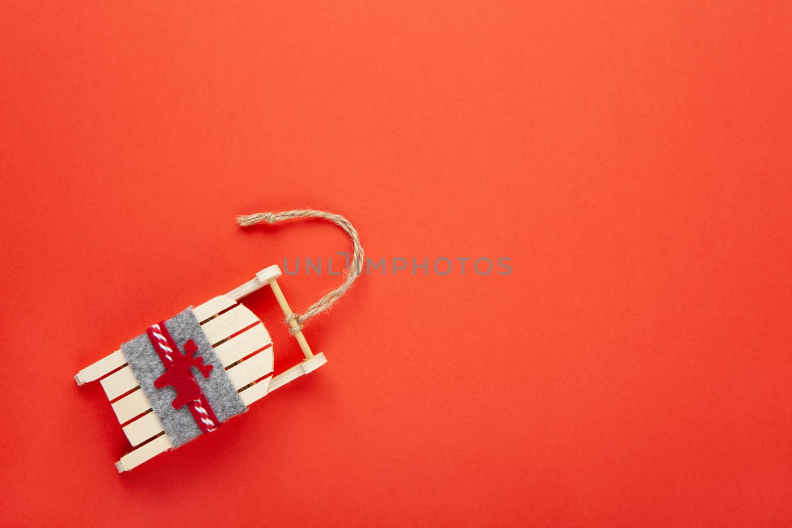 Christmas decoration, tree toy, wooden sled with deer on red background with copy space. Festive, New Year concept. Horizontal, flat lay. Minimal style. Top view.