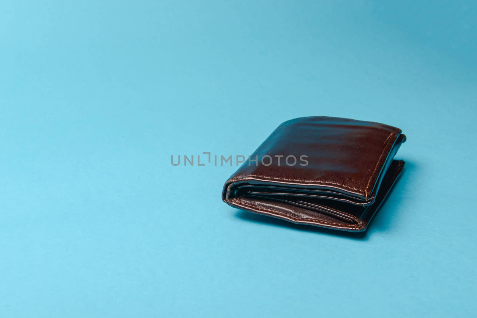 brown mans leather wallet on a blue background