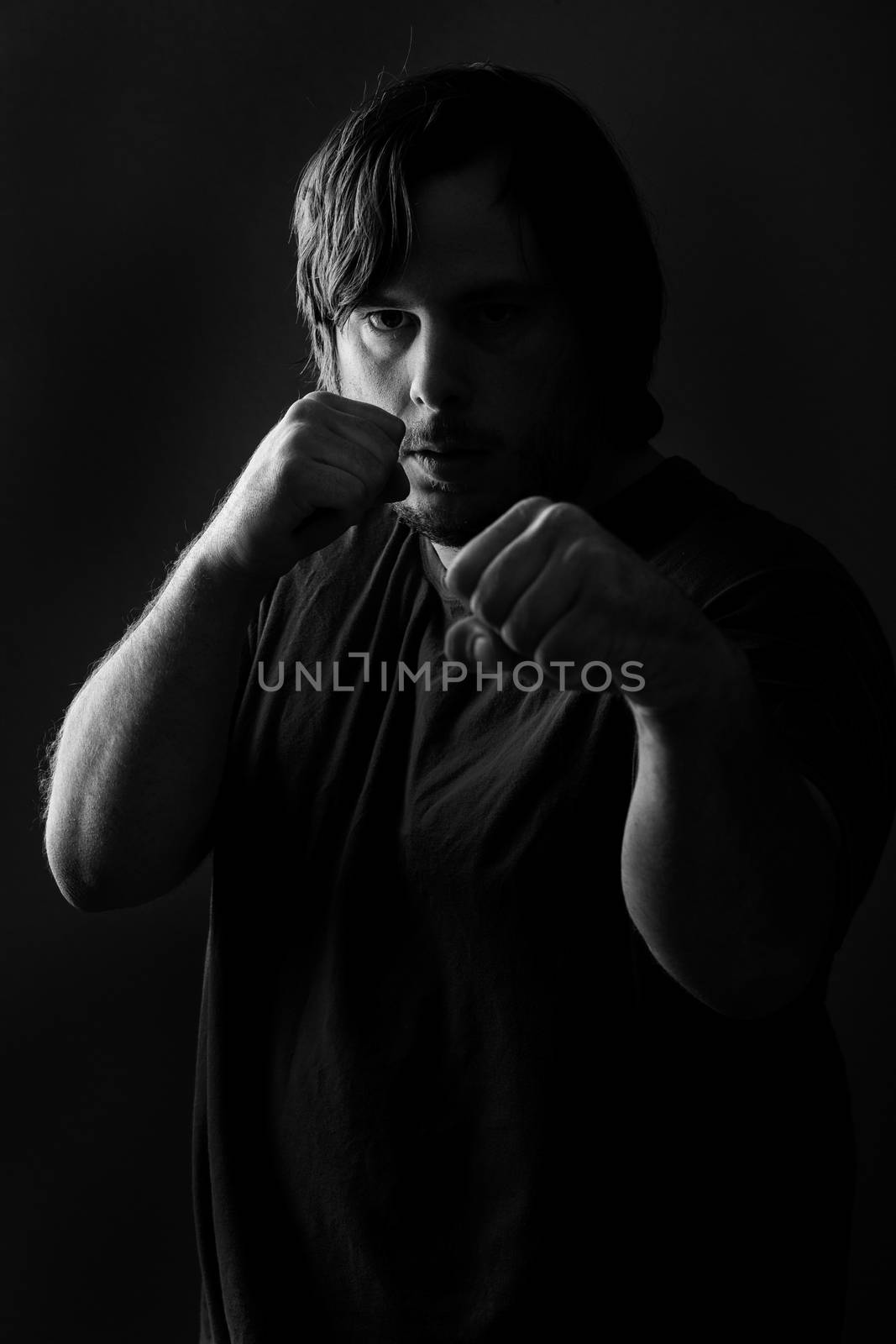 Low key photo of a heavy set guy getting ready to fight.
