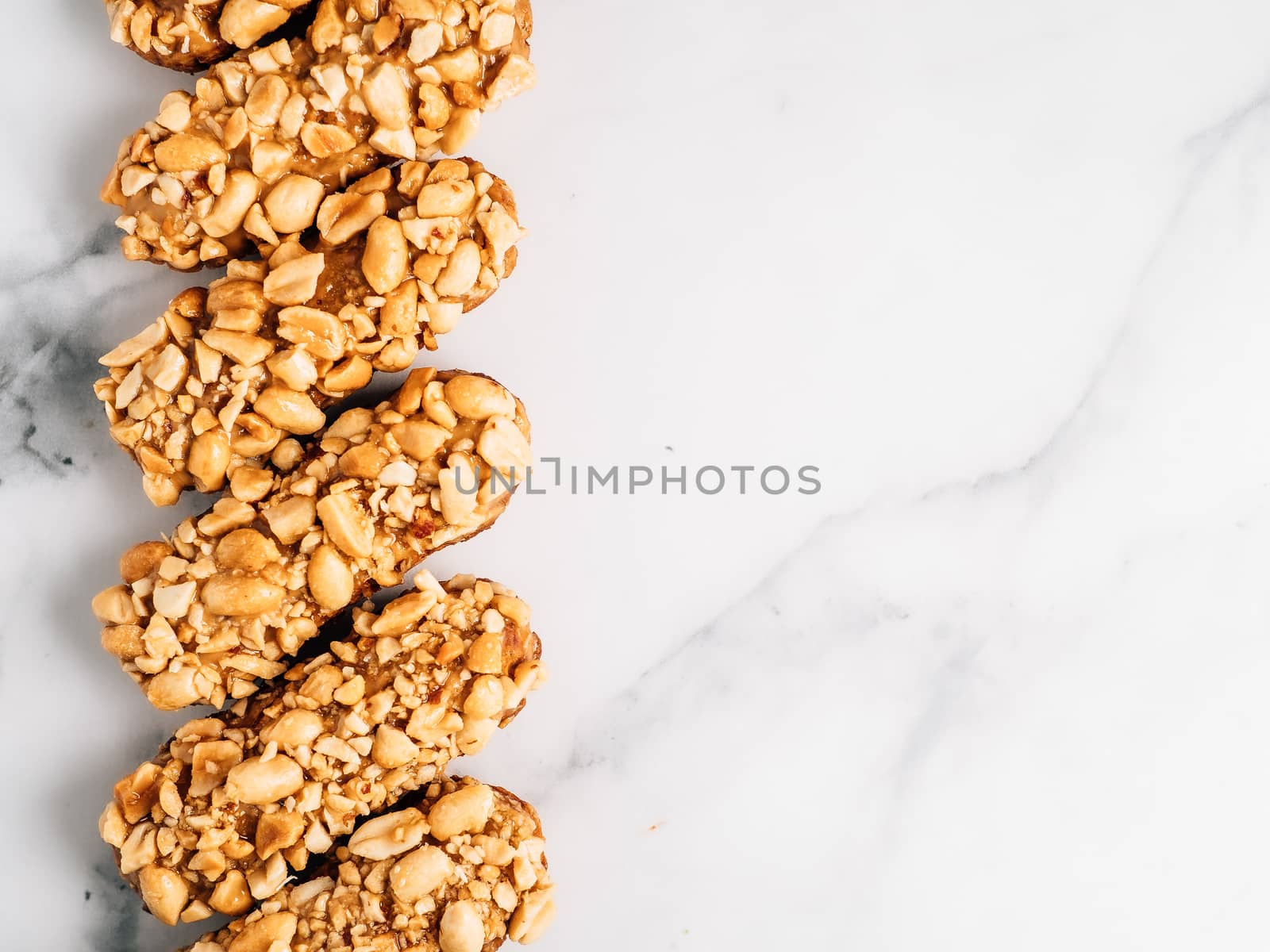 Set of homemade eclairs with peanut decor on marble background. Top view of delicious healthy profitroles with nuts. Copy space for text or design.