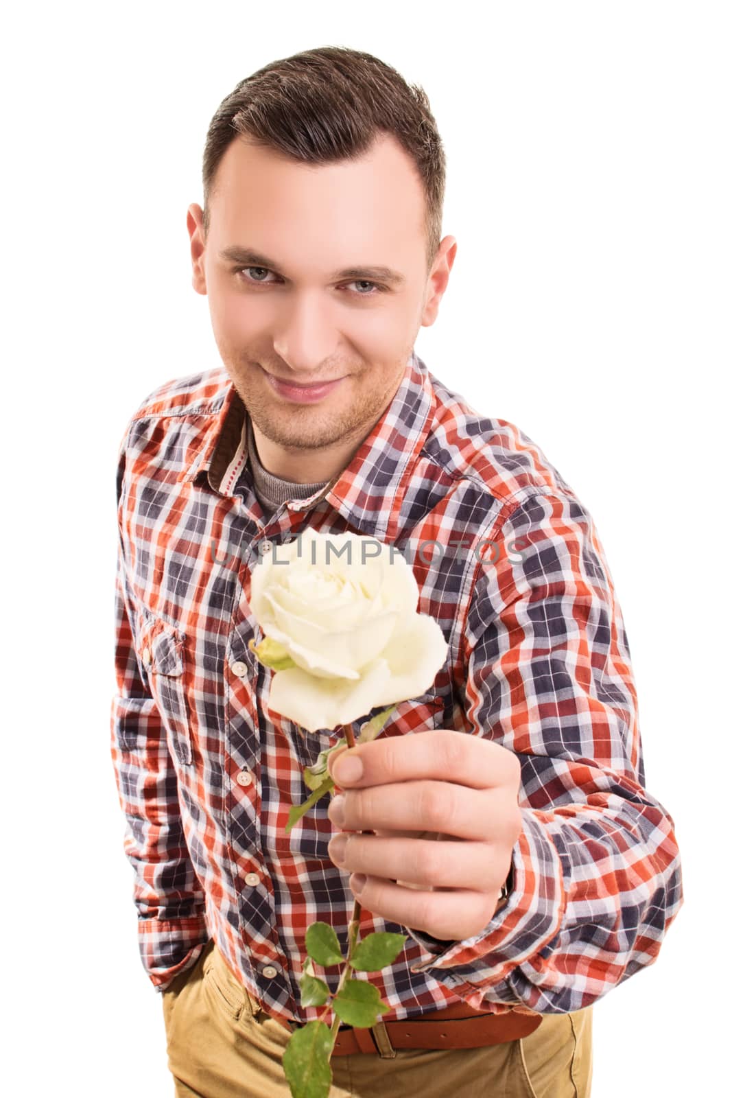 Close up portrait of a smiling handsome young man giving a white rose flower to you while standing, isolated on white background.
