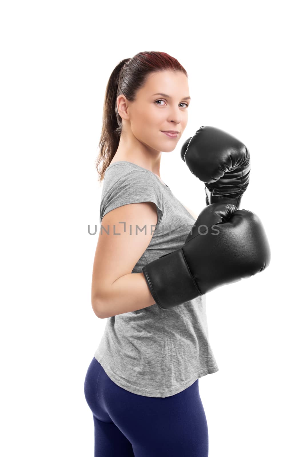 Portrait of a beautiful young woman with boxing gloves in a stance with raised arms, isolated on white background.